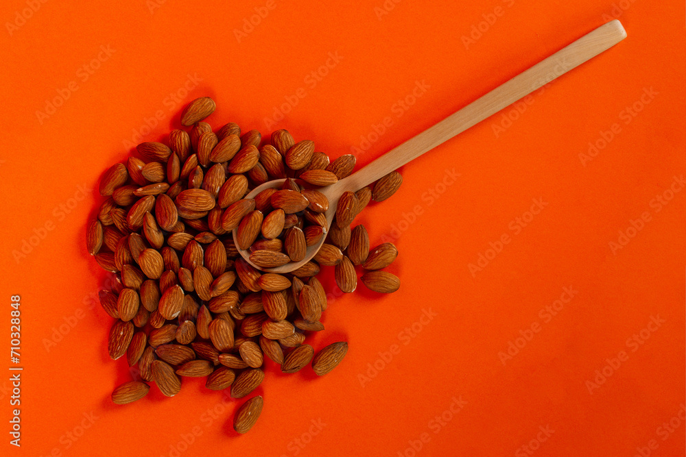 Seed almonds in spoon wooden on orange background.Top view