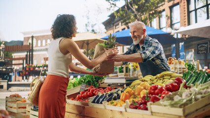 Cheerful Street Vendor Running a Small Farm Market Business, Selling Sustainable Fruits and Vegetables. Happy Middle Aged Man Filling a Recycled Paper Shopping Bag with Local Natural Food