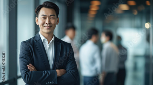 Portrait of a handsome smiling asian businessman boss standing in his modern business company office. © Farnaces