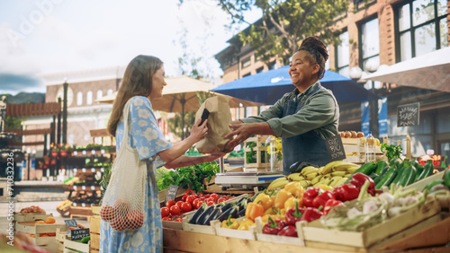 Beautiful Female Customer Buying Sustainable Organic Vegetables From a Joyful Black Female Farmer on a Sunny Summer Day. Successful Street Vendor Managing a Farm Stall at an Outdoors Eco Market photo