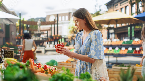 Woman Shopping for Fresh Vegetables from a Local Farm Market Stall. Young Beautiful Female Choosing Red Bell Peppers and Tomatoes from a Selection with Organic Chemical-Free Produce 
