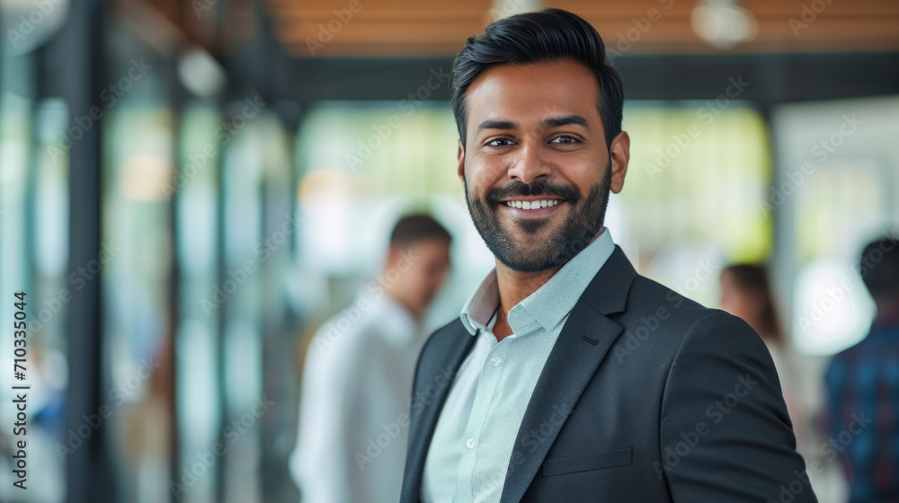 Portrait of a handsome smiling asian indian businessman boss standing in his modern business company office. Portrait of a handsome smiling asian indian businessman boss standing in his modern business company office.