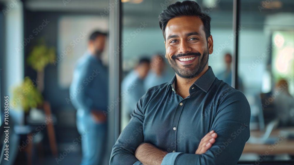 Portrait of a handsome smiling asian indian businessman boss standing in his modern business company office.