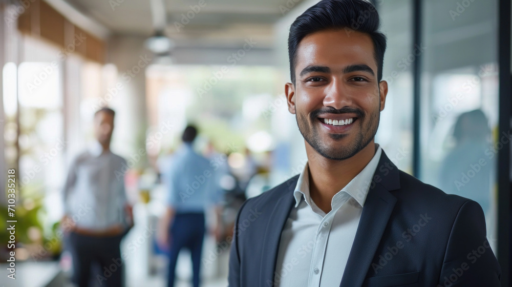 Portrait of a handsome smiling asian indian businessman boss standing in his modern business company office. Portrait of a handsome smiling asian indian businessman boss standing in his modern business company office.