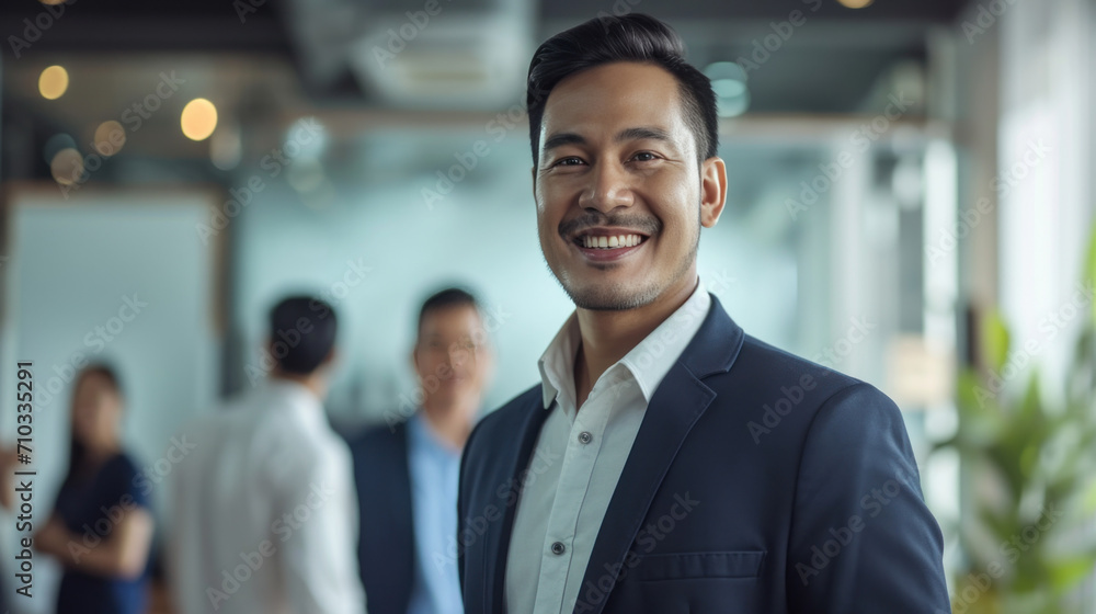 Obraz premium Portrait of a handsome smiling asian indian businessman boss standing in his modern business company office.