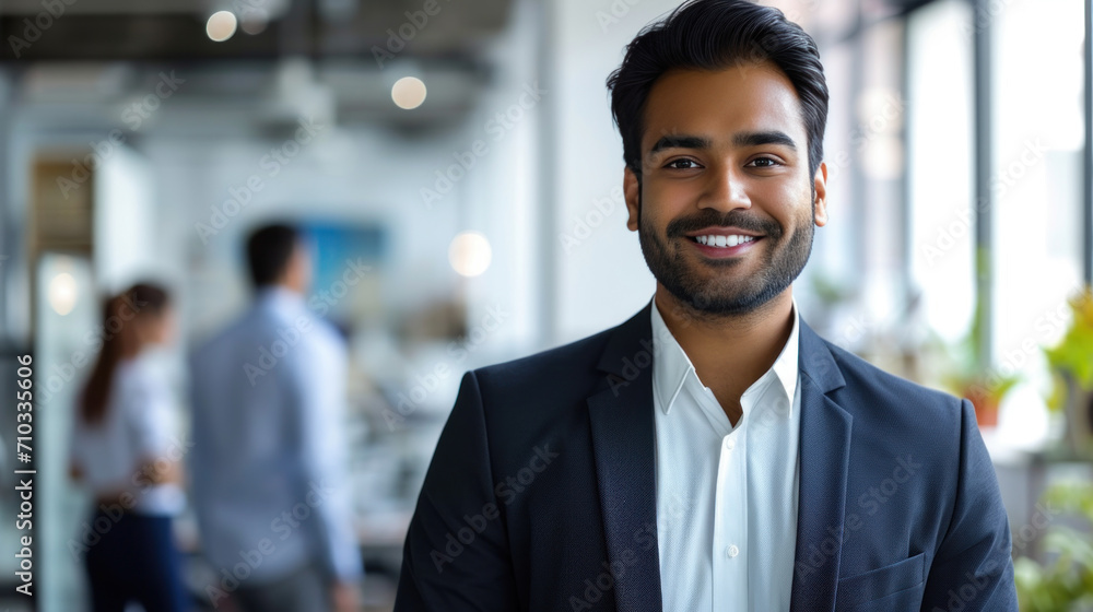 Portrait of a handsome smiling asian indian businessman boss standing in his modern business company office. Portrait of a handsome smiling asian indian businessman boss standing in his modern business company office.
