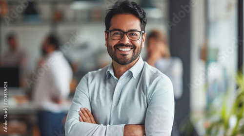 Portrait of a handsome smiling asian indian businessman boss standing in his modern business company office. © Farnaces