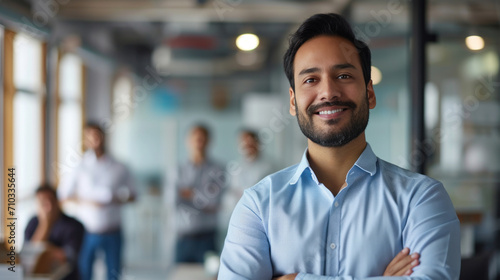 Portrait of a handsome smiling asian indian businessman boss standing in his modern business company office.