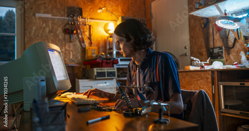Portrait Of Caucasian Male Software Engineer Programming on Old Desktop Computer In Retro Garage In The Evening. Man Starting Tech Startup Company In Nineties. Coding Innovative Online Service At Home
