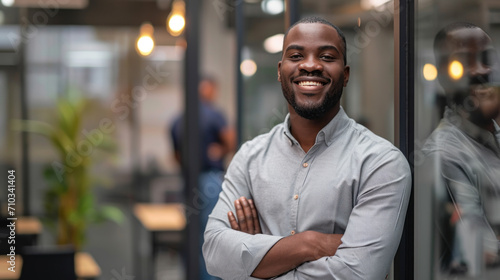 Portrait of a handsome smiling black businessman boss standing in his modern business company office. © Farnaces