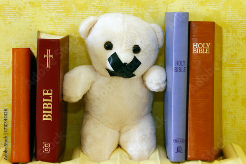 Bibles and teddy bear with tape on his mouth. Symbol of silence on child abuse and victim in christian church. photo