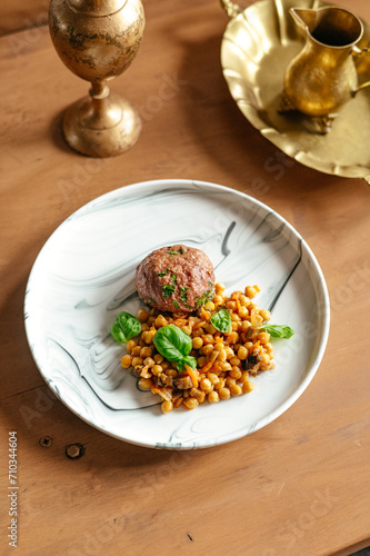 beef patty on a plate with a side dish of chickpeas and sauce