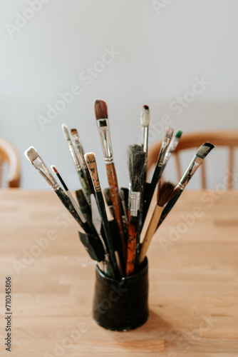 A mug of paint brushes of different sizes in the art studio