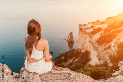 A portrait of a woman in white shorts and T-shirt with long hair, standing against the sea, showcasing her joyful and contented mood. © svetograph