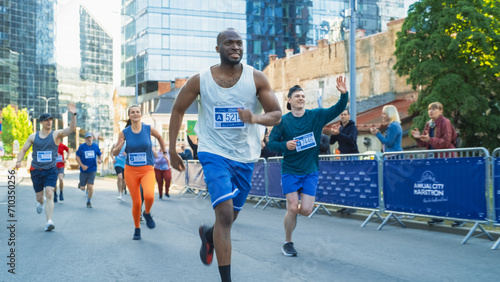 Portrait of Smiling Young Black Man Running in a City Marathon, Waving at the Supportive Audience. Friendly Happy Male Runner Celebrating Crossing the Finish Line in a Race