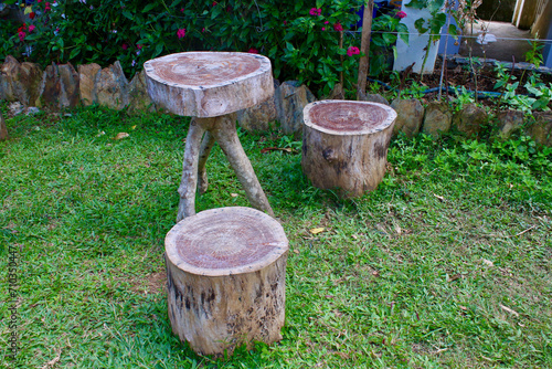 Homemade wooden table and chairs from stumps. A table made of a tree trunk and two stumps near a house in the village.