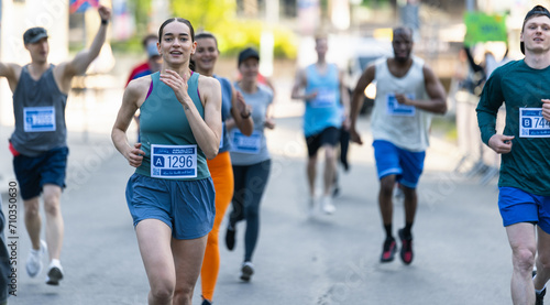Diverse Group of People Running a Marathon in a City During the Day. Active and Fit Smiling Female Runner Competing to Reach the Finish Line, Supported by Friends and Family