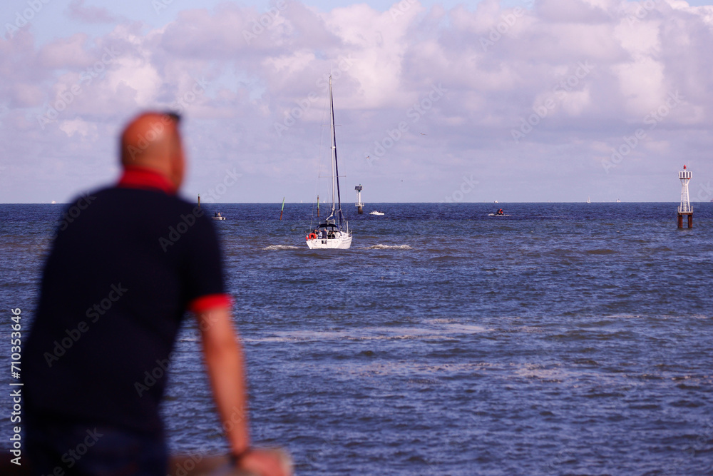Back view of a man watching boats on the sea.  Trouville. France.