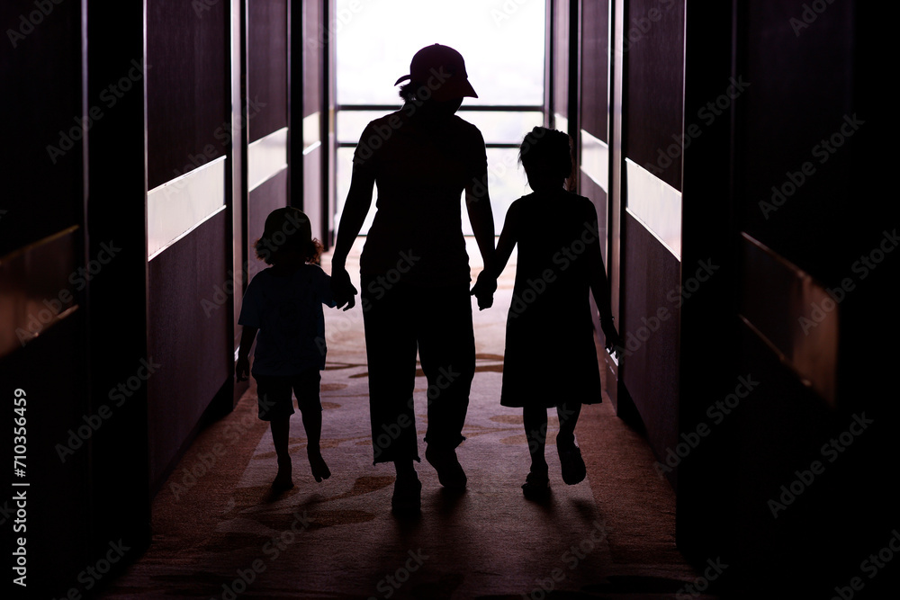 Adult with children. Silhouette. Woman holding hands of boy and girl. One parent family concept.