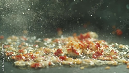 Garlic and red chili frying with olive oil in steel pan hot and boiling slow motion photo
