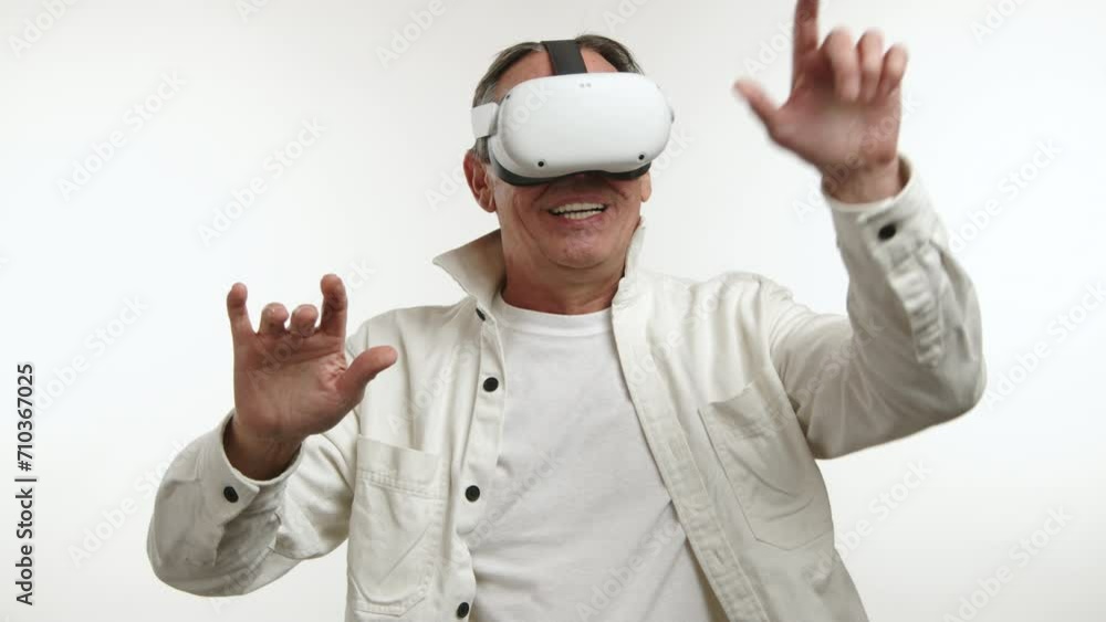 Excited middle-aged man in a virtual reality headset, gesturing and interacting with unseen digital content, wearing a casual white jacket on a white background. Camera 8K RAW. Excited middle-aged man in a virtual reality headset, gesturing and interacting with unseen digital content, wearing a casual white jacket on a white background. Camera 8K RAW.