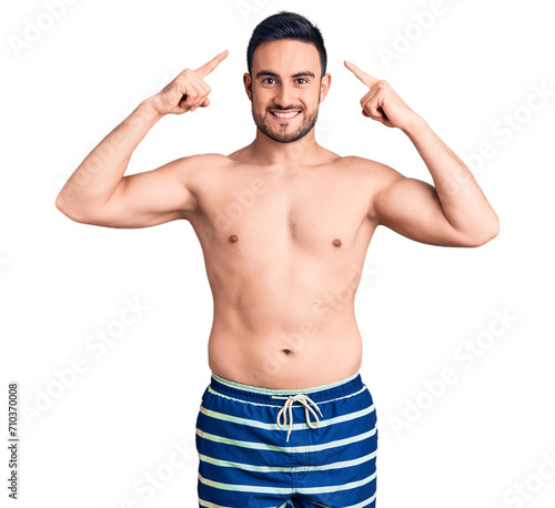 Young handsome man wearing swimwear smiling pointing to head with both hands finger, great idea or thought, good memory