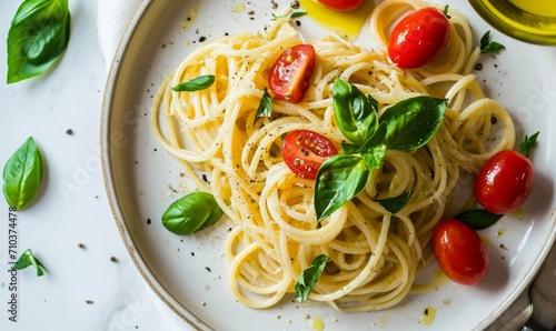 Top view of spaghetti with cherry tomatoes and basil on a white plate.