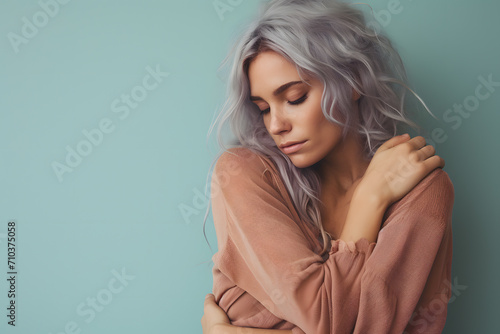 Young woman hugging herself in front of one colored studio background. Self-love concept