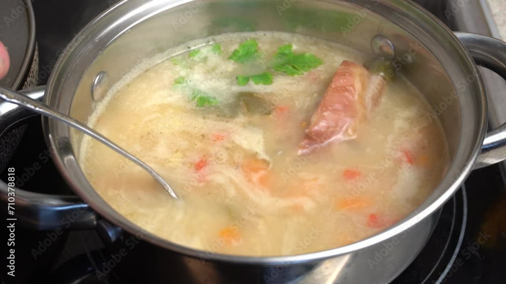 Rich, aromatic pea soup with smoked ribs is cooked in a saucepan on the kitchen stove. Mix of carrots, potatoes, ribs, onions and peas. Close-up. Rich, aromatic pea soup with smoked ribs is cooked in a saucepan on the kitchen stove. Mix of carrots, potatoes, ribs, onions and peas. Close-up.