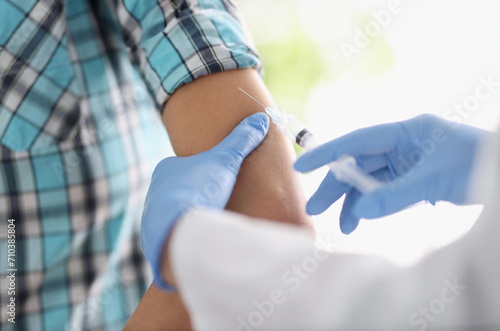 Doctor gives patient an injection in shoulder. Vaccination of population against infectious diseases concept