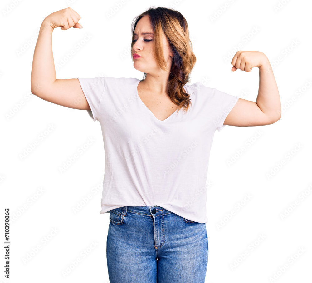 Young beautiful caucasian woman wearing casual white tshirt showing arms muscles smiling proud. fitness concept. Young beautiful caucasian woman wearing casual white tshirt showing arms muscles smiling proud. fitness concept.