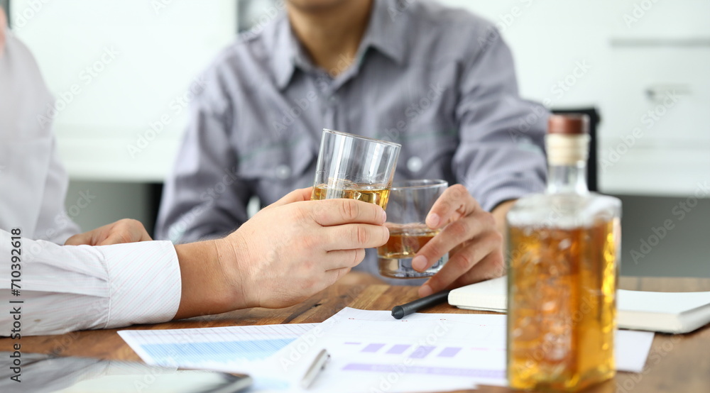 Two business men drinking cognac from glasses at workplace closeup. Celebrating business success concept