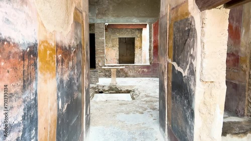 The interior of an ancient Roman house in Pompeii, showing faded frescoes on the walls and a central stone table in an atrium. photo