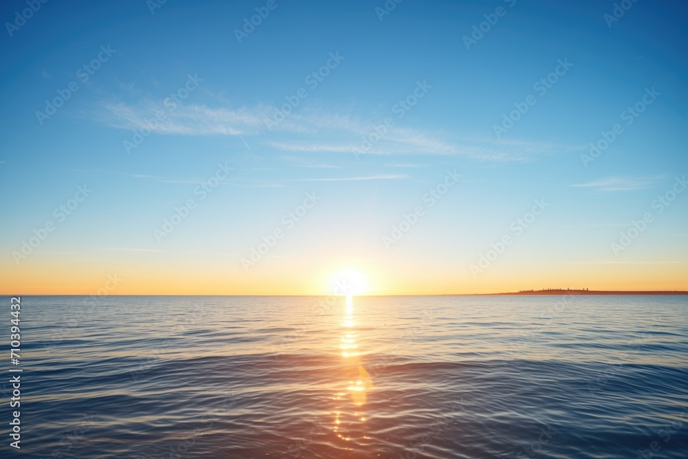 sunrise over calm ocean with clear blue sky