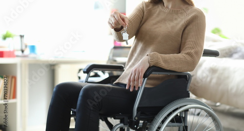 Woman in wheelchair holding apartment key closeup. Social support for people with disabilities concept