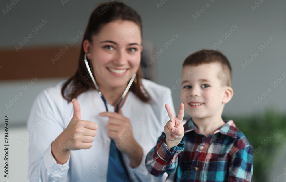 Young smiling doctor and child showing thumbs up closeup. Pediatrics examination and treatment of children concept Young smiling doctor and child showing thumbs up closeup. Pediatrics examination and treatment of children concept