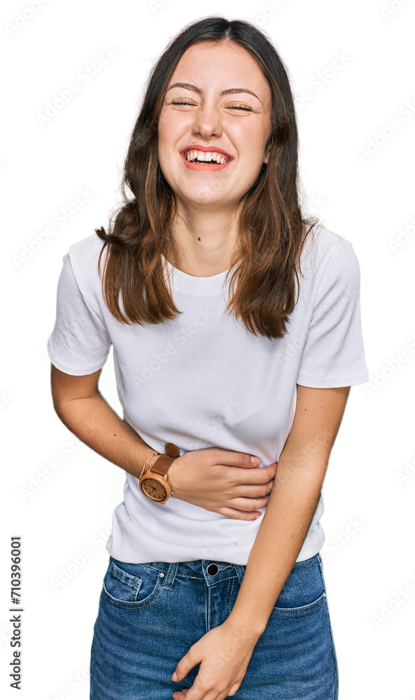 Young beautiful woman wearing casual white t shirt smiling and laughing hard out loud because funny crazy joke with hands on body. Young beautiful woman wearing casual white t shirt smiling and laughing hard out loud because funny crazy joke with hands on body.