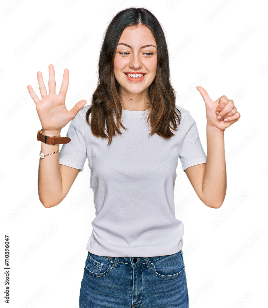Young beautiful woman wearing casual white t shirt showing and pointing up with fingers number six while smiling confident and happy. Young beautiful woman wearing casual white t shirt showing and pointing up with fingers number six while smiling confident and happy.