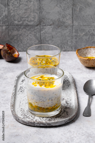 Chia pudding with passion fruit puree and yogurt in a glass on a grey background. Healthy vegetarian food. Tasty breakfast idea. Parfait with tropical fruit.