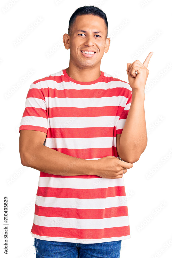 Young handsome latin man wearing casual clothes with a big smile on face, pointing with hand and finger to the side looking at the camera. Young handsome latin man wearing casual clothes with a big smile on face, pointing with hand and finger to the side looking at the camera.