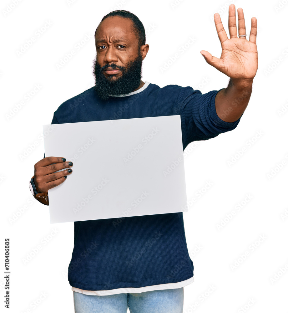 Young african american man holding blank empty banner with open hand doing stop sign with serious and confident expression, defense gesture Young african american man holding blank empty banner with open hand doing stop sign with serious and confident expression, defense gesture
