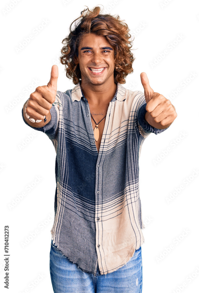 Young hispanic man wearing summer style approving doing positive gesture with hand, thumbs up smiling and happy for success. winner gesture. Young hispanic man wearing summer style approving doing positive gesture with hand, thumbs up smiling and happy for success. winner gesture.