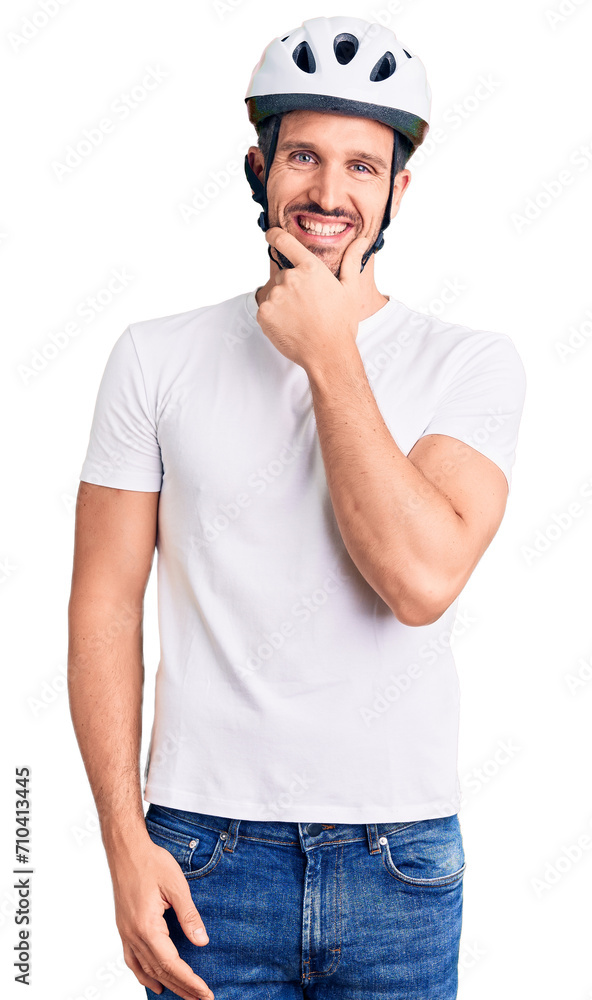 Young handsome man wearing bike helmet looking confident at the camera smiling with crossed arms and hand raised on chin. thinking positive.