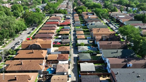 Chicago suburb with rows of brown-roofed houses and green yards in summer. Aerial flight above urban sprawl, backyards in neighborhood. photo