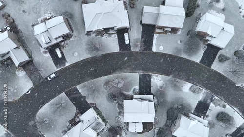 Snow flurries laying on houses and homes in USA neighborhood. Aerial top down shot of cul-de-sac during snow storm. photo