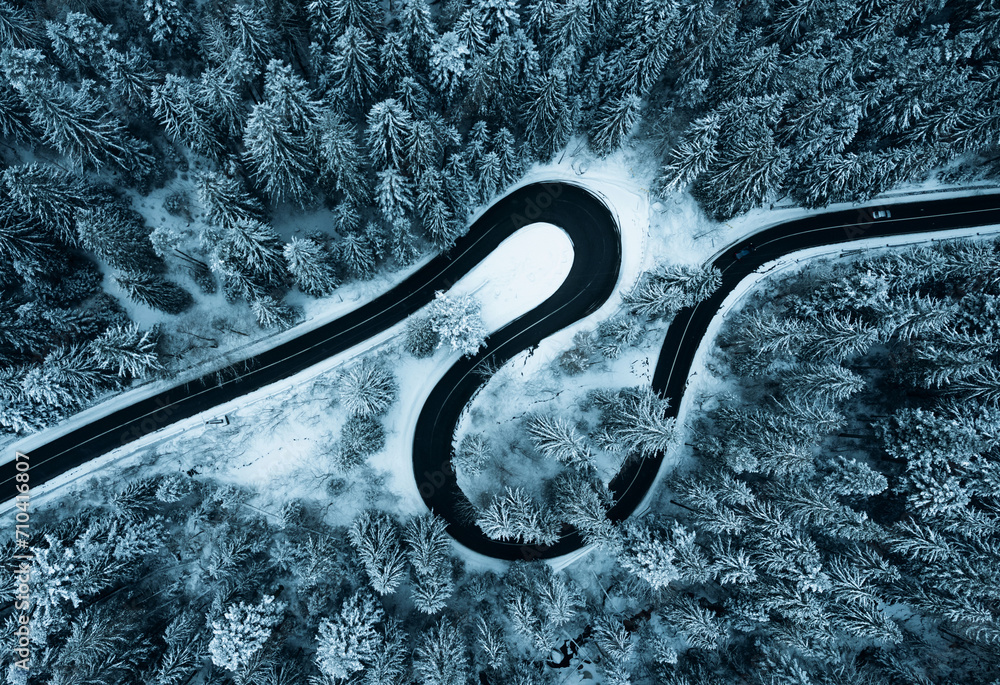 Aerial view of snowy forest with amazing curved road. Top photo taken with a drone.