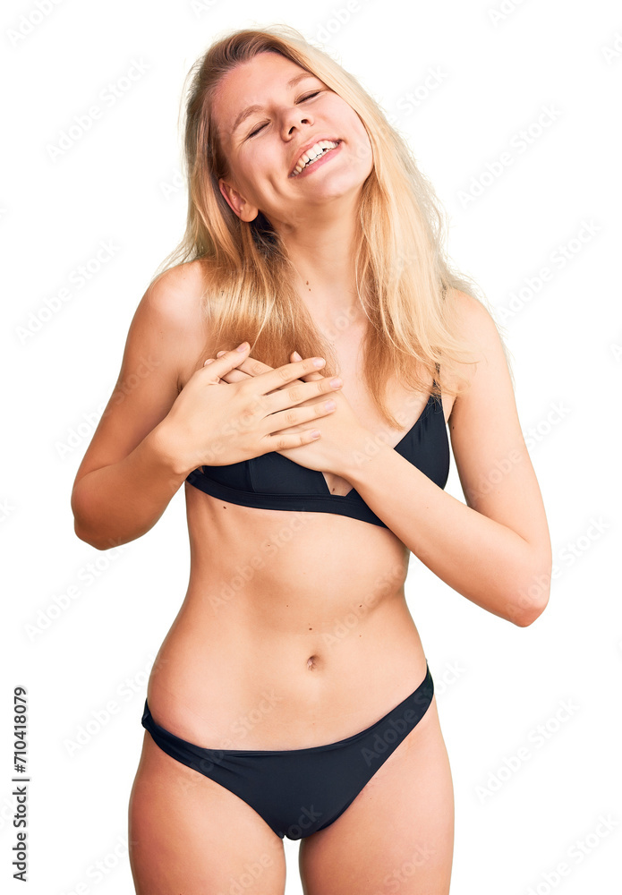 Fototapeta premium Young beautiful blonde woman wearing bikini smiling with hands on chest with closed eyes and grateful gesture on face. health concept.
