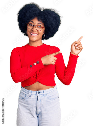 Young african american girl wearing casual clothes and glasses smiling and looking at the camera pointing with two hands and fingers to the side.