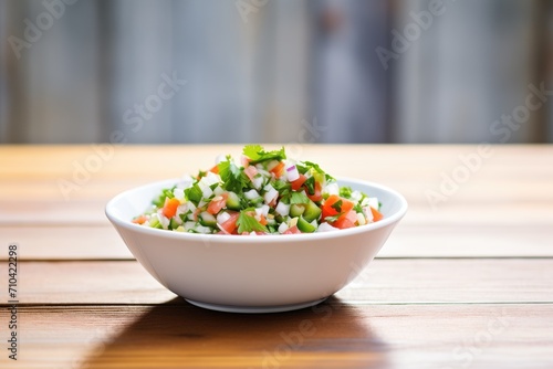 fresh pico de gallo in a white bowl on a wooden table