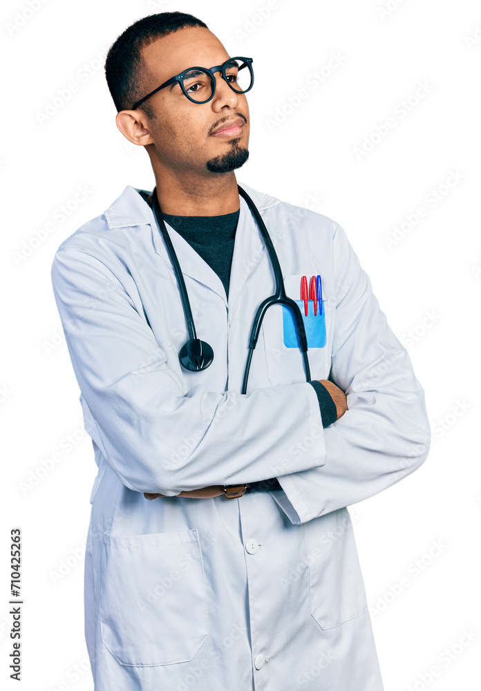 Young african american man wearing doctor uniform and stethoscope looking to the side with arms crossed convinced and confident